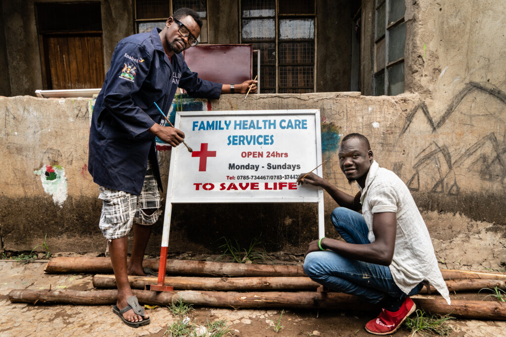 two men painting a healthcare board